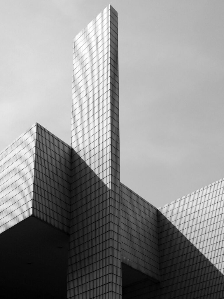 From below black and white of contemporary geometric construction exterior with tall walls under light cloudy sky in sunny day